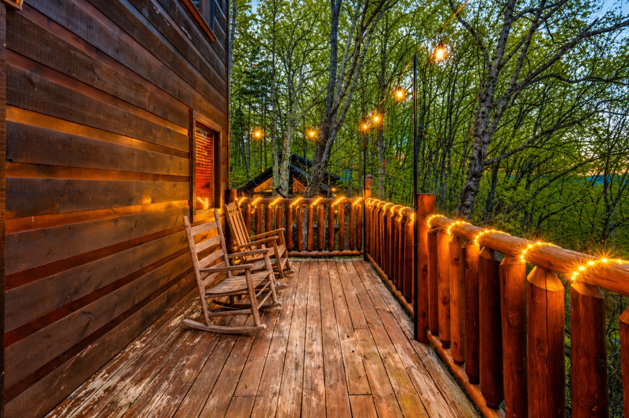 Rocking chairs on Bearadise's upper deck, strung with string lights at dusk